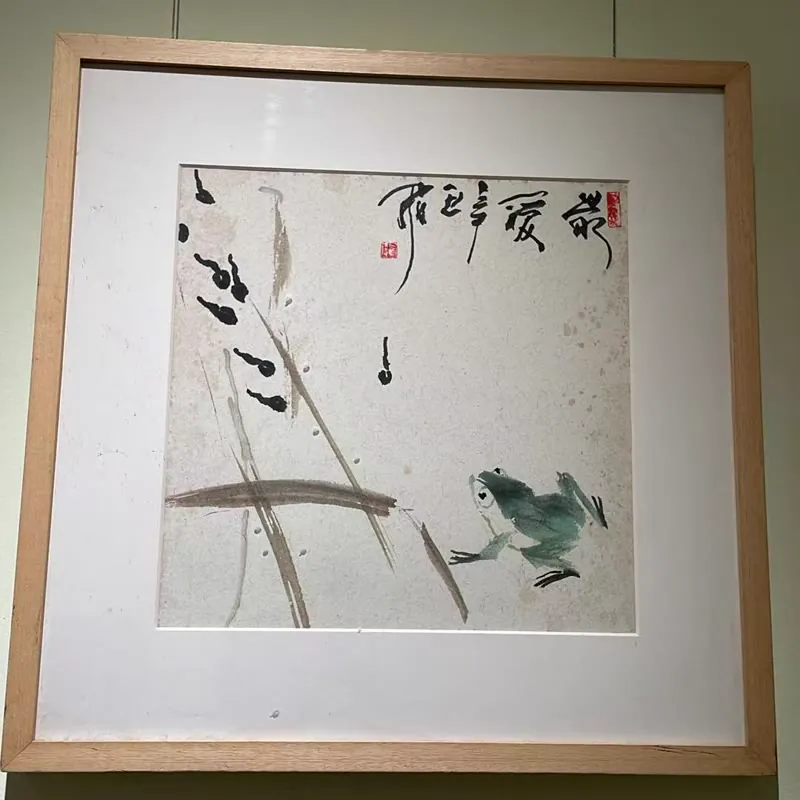 Framed ink painting of a frog among reeds