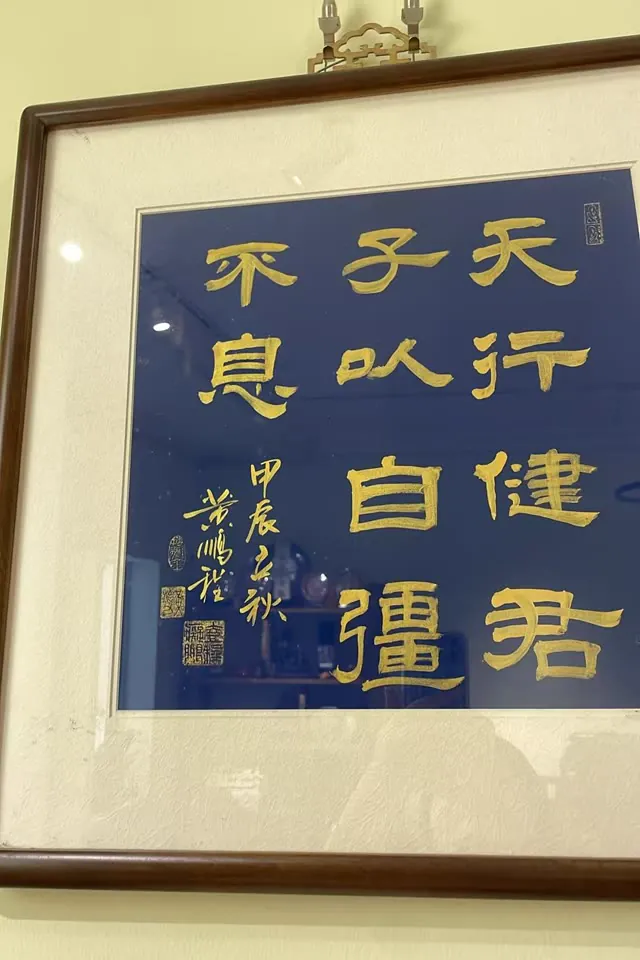 Framed calligraphy in gold on deep blue: 天行健，君子以自强不息